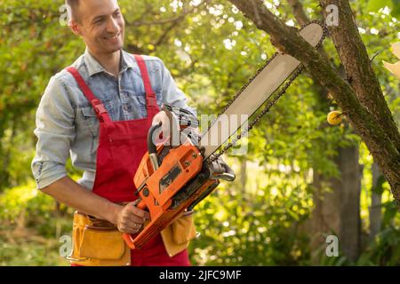 beau jeune homme jardinier taille hedgerow dans un parc de jardin à l'extérieur. Banque D'Images