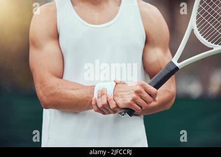 Un joueur de tennis de course mixte inconnu souffrant de blessures au poignet dans un jeu de court. Hispanique FIT professionnel dans la douleur tout en tenant et frottant la main après Banque D'Images