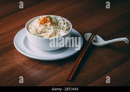 Un bol de riz frais savoureux avec des légumes et des bâtonnets de bois sur une table Banque D'Images