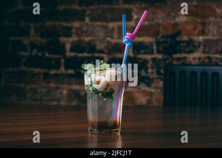 Un gros plan d'un cocktail à la menthe et au litchi dans un verre avec des pailles sur une table en bois Banque D'Images