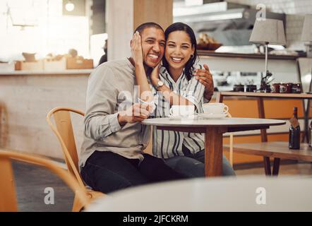 Portrait de jeune couple de race mixte aimant ayant un café tout en étant assis à table dans un café. Belle jeune femme tenant son visage de boyamis et Banque D'Images