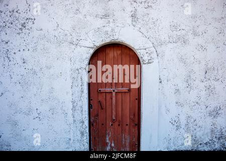 Porte en bois d'un ermitage dans la ville 'la Peral' à Somiedo, Asturias, Espagne. La porte est entourée d'une croix clouée en bois et d'une voûte Banque D'Images