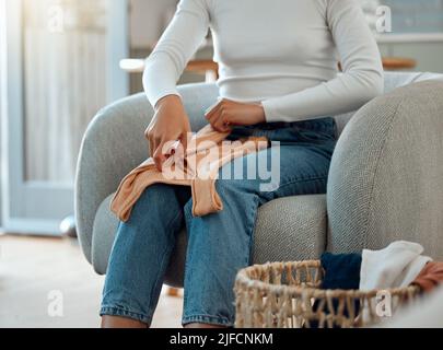 Femme assise sur une chaise pliante linge. Femme nettoyant ses vêtements, faisant des travaux ménagers. Femme qui fait des corvées à la maison. Femme de race mixte terminant Banque D'Images