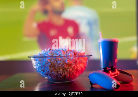 Sports jeux vidéo. Un match sportif sur grand écran de télévision. Football, basket-ball, football américain. Sur la table se trouve un bol de pop-corn, une boisson dans un plas Banque D'Images