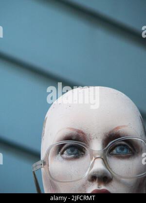 Partie supérieure de la tête de mannequin avec des yeux bleus et des lunettes transparentes sur fond de maison bleue à San Francisco, Californie Banque D'Images