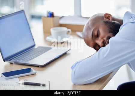 Un jeune homme d'affaires afro-américain dormant à son bureau au travail. Homme d'affaires fatigué utilisant un ordinateur portable et se mettre à faire une pause au travail Banque D'Images