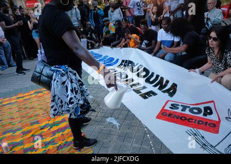 Pampelune, Espagne. 01st juillet 2022. Un manifestant de couleur, déverse du lait à côté d'une bannière qui se lit, «coupable Europe, Arrêter le génocide» lors d'une manifestation tenue à Pampelune. Près d'un millier de personnes ont manifesté aujourd'hui à Pampelune avec le slogan: La vie noire compte avec le hashtag #MasacreMelilla, en condamnation de plus de 35 meurtres aux mains de la police marocaine quand ils ont essayé de sauter la barrière qui sépare l'Afrique de l'Espagne sur 25 juin 2022. Crédit : SOPA Images Limited/Alamy Live News Banque D'Images