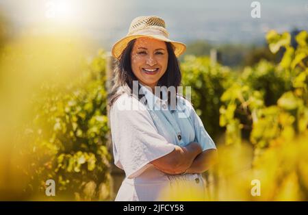 Une race mixte mûre souriante ferme confiante debout avec ses bras croisés sur son vignoble avec copyspace. Femme hispanique mature avec ses bras Banque D'Images