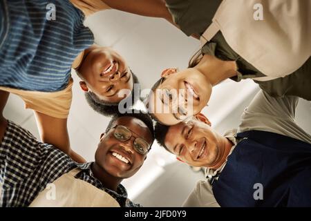 Portrait d'un groupe de créateurs de mode en caucus. Les tailleurs heureux se sont unis dans un cercle d'en bas. Divers hommes d'affaires collaborent ensemble Banque D'Images