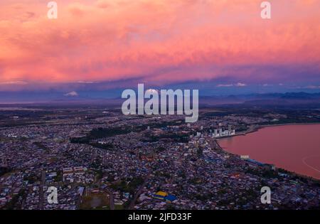 vista aérea de la Ciudad de Puerto Montt al atardecer, con los volcanes andinos al fondo y hermosos colores del atardecer en las nubes Banque D'Images