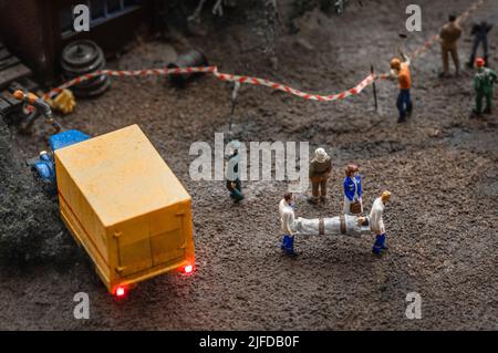 Représentation en jouet de deux ambulanciers paramédicaux portant une civière avec un homme allongé dans celle-ci. Banque D'Images