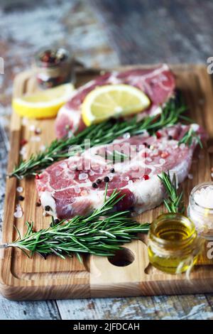 Steaks de porc crus au romarin, au gros sel et au citron. Porc frais. Steak de cou. Céto à la viande biologique Pega. Alimentation Paleo. Banque D'Images