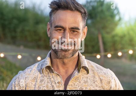 Beau portrait d'homme posant souriant dans la nature en arrière-plan dans la nuit d'été. Banque D'Images