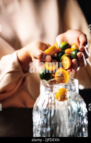 Remplissage du pot de boisson avec des kumquats et de petites limes, frais et fruité de boisson froide processus de fabrication - photo de stock Banque D'Images