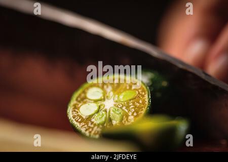 Couper la petite lime en deux, fraîche et fruitée de la boisson froide processus de fabrication - photo de stock Banque D'Images