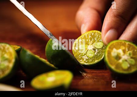 Couper la petite lime en deux, fraîche et fruitée de la boisson froide processus de fabrication - photo de stock Banque D'Images