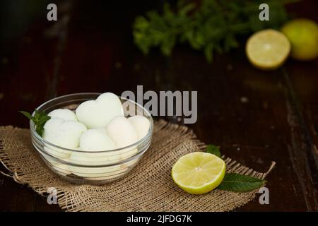 Guimauves naturelles en forme de coeur sur la spicking dans la soucoupe en verre sur la succion. Décorations à la menthe et au citron vert. Dessert frais et sain. Banque D'Images