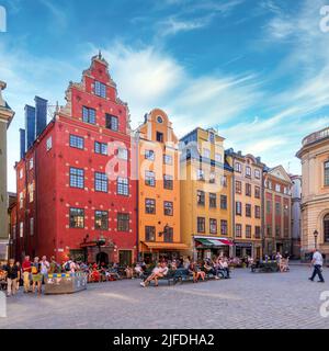 Stockholm, Suède - 26 juin 2022: Stortorget, la grande place, à Gamla Stan, la vieille ville, avec des vieux bâtiments traditionnels colorés pendant une journée d'été avec les touristes et les habitants à pied et assis dans les cafés Banque D'Images