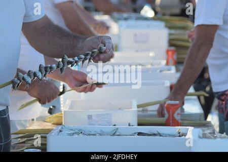 Espeteros skewering sardines. Sardines espetos, cuisine typiquement espagnole Banque D'Images