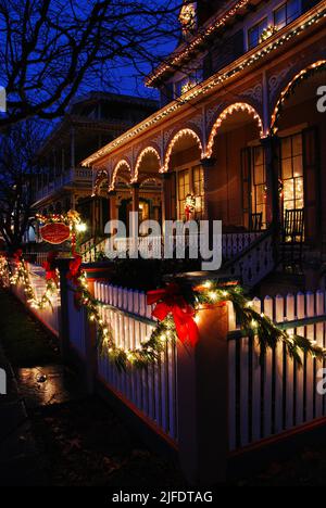 Une belle maison victorienne est décorée de houx et de lumières le long d'une clôture de cornichons blancs à Noël à Cape May sur la rive du New Jersey Banque D'Images