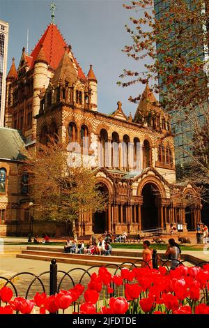 Les gens se détendent dans la place publique Copley Square, en face de Trinity Church, lors d'une journée de printemps entourée de tulipes dans le quartier de Back Bay à Boston Banque D'Images