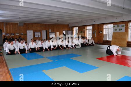 Groupe de stagiaires en kimono s'agenouillant sur le tatami à l'écoute de l'instructeur d'aikido avant de s'entraîner dans un club sportif. 6 février 2018. Kiev, Ukraine Banque D'Images