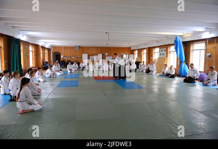 Groupe de stagiaires en kimono s'agenouillant sur le tatami à l'écoute de l'instructeur d'aikido avant de s'entraîner dans un club sportif. 6 février 2018. Kiev, Ukraine Banque D'Images