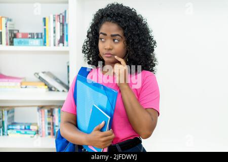 Penser une étudiante brésilienne avec un sac à dos et de la paperasse dans la salle de classe de l'université Banque D'Images