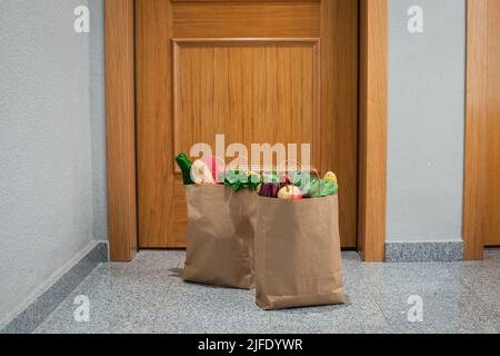 Des sacs de shopping de nourriture sont à la porte de la maison ou de l'appartement.Livraison de légumes et de fruits pendant la quarantaine et l'auto-isolement. Banque D'Images