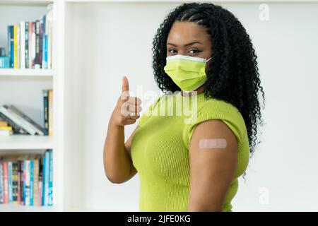 Jolie jeune femme afro-américaine avec du plâtre après vaccination contre Covid-19 comme symbole d'injection contre le coronavirus Banque D'Images