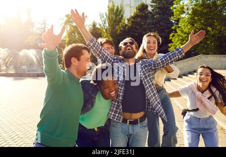 Un groupe d'amis joyeux s'amusent, se réjouissent, rient et se huent tout en marchant dans les rues de la ville. Banque D'Images