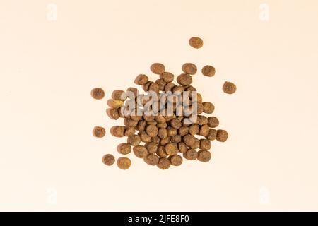 Une poignée de nourriture sèche pour les chats et les chiens sur un fond beige. Vue de dessus Banque D'Images