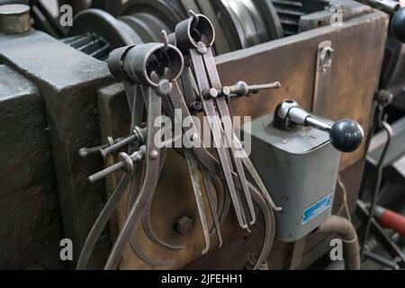 Gros plan d'un équipement spécial de mesure comme des étriers, des diviseurs et une boussole de l'ancienne machine de tournage. Machines industrielles d'époque dans une ancienne usine. Banque D'Images