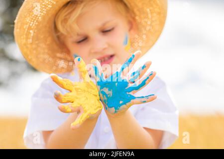 Arrêtez la guerre en Ukraine. Love Ukraine concept. Un garçon ukrainien avec drapeau ukrainien - jaune et bleu peint sur les mains se tient contre la guerre. Banque D'Images