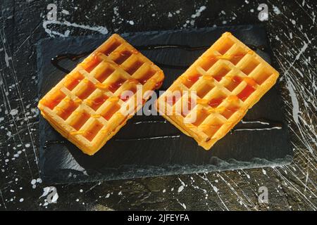 Gaufres sucrées servies avec du miel sur un tableau d'ardoise Banque D'Images