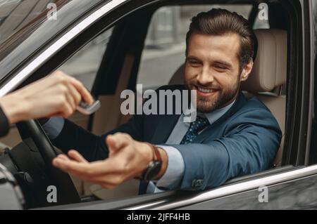 Gros plan portrait d'un homme d'affaires souriant et confiant qui obtient les clés du vendeur Banque D'Images