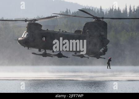 Un ingénieur de combat de l'Armée de terre de la Compagnie Breacher, 6th Brigade Engineer Battalion (Airborne), 2nd Infantry Brigade combat Team (Airborne), 11th Airborne Division, saute d'un CH-47F Chinook de l'Armée pendant l'entraînement d'héliocast au lac Clune, base interarmées Elmendorf-Richardson, Alaska, 29 juin 2022. Les ingénieurs de combat ont mené les opérations d'hélicast pour établir la confiance et se familiariser avec les formations futures qu'ils rencontreront. L'équipage de la Compagnie B, 1-52nd, Bataillon de l'aviation de soutien général, a fourni un appui aérien pour l'entraînement. (É.-U. Photo de la Force aérienne par Alejandro Peña) Banque D'Images