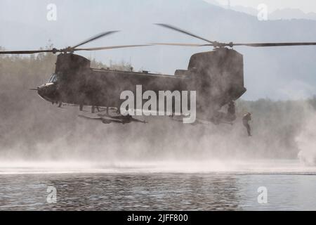 Un ingénieur de combat de l'Armée de terre de la Compagnie Breacher, 6th Brigade Engineer Battalion (Airborne), 2nd Infantry Brigade combat Team (Airborne), 11th Airborne Division, saute d'un CH-47F Chinook de l'Armée pendant l'entraînement d'héliocast au lac Clune, base interarmées Elmendorf-Richardson, Alaska, 29 juin 2022. Les ingénieurs de combat ont mené les opérations d'hélicast pour établir la confiance et se familiariser avec les formations futures qu'ils rencontreront. L'équipage de la Compagnie B, 1-52nd, Bataillon de l'aviation de soutien général, a fourni un appui aérien pour l'entraînement. (É.-U. Photo de la Force aérienne par Alejandro Peña) Banque D'Images