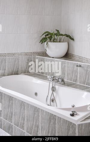 Baignoire blanche avec robinet en métal dans la salle de bains moderne dans le style minimaliste de l'appartement Banque D'Images