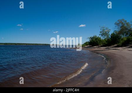 Ryokana de froid profond dans le nord de la Russie. Les saisons sont l'été. Une plage de sable avec des buissons verts qui s'y développent. Nuages blancs dans le ciel bleu Banque D'Images