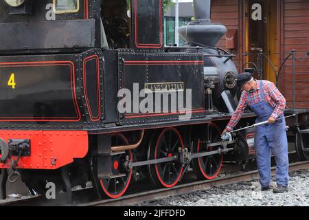 Uppsala, Suède - 2 juillet 2022 : une vieille locomotive à vapeur à voie étroite dans la circulation des musées est lubrifiée par le personnel ferroviaire de la gare de l'est d'Uppsala. Banque D'Images