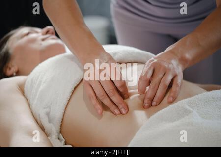Vue de dessus des mains massant l'abdomen de la femme. Thérapeute appliquant une pression sur le ventre. Femme recevant un massage au spa, japonais Chi Nei, gros plan Banque D'Images