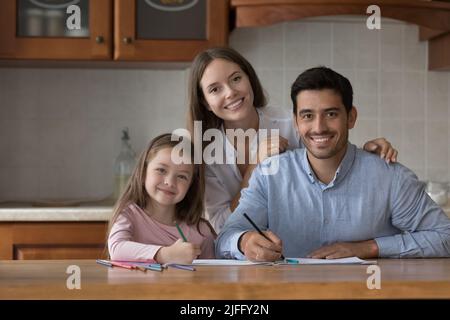 Les parents et la fille dessin avec des crayons sourire regarder l'appareil photo Banque D'Images