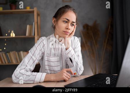 Ennuyé jeune fille assis à la table de bureau à la maison regarder et travailler à l'ordinateur portable, femme épuisée étudiant se sentent non motivé, distrait. Travail monotone Banque D'Images