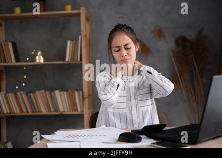 jeune femme fatiguée frottant son cou raide massant les muscles tendus, la mauvaise posture et le travail sédentaire, la fibromyalgie, la mauvaise posture Banque D'Images