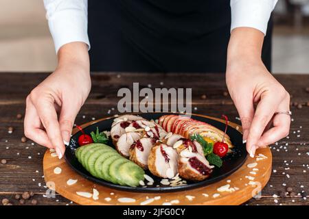 Un garçon sert du veau cuit avec des fruits frais Banque D'Images