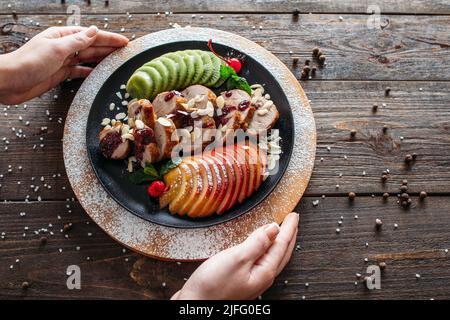 Un garçon sert du veau cuit avec des fruits frais Banque D'Images