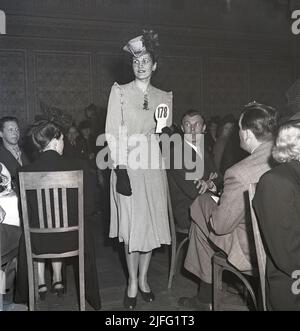 La mode des femmes en 1940s. Une jeune femme tenue en 1946. Une robe à la bonne longueur, chapeau et gants assortis. Le défilé de mode de la mode féminine de cette année se poursuit devant les gens dans un public. Suède 1946 Kristoffersson T148-6 Banque D'Images