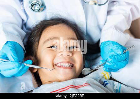 Examen de santé dentaire des enfants. Le docteur examine la cavité buccale de petit enfant utilise le miroir de la bouche pour vérifier la cavité dentaire, le dentiste asiatique faisant l'examinatio Banque D'Images