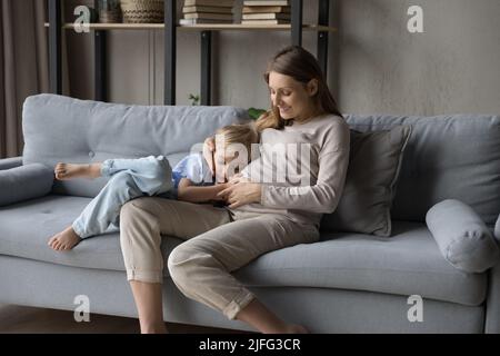 Une femme enceinte et un fils d'âge préscolaire s'assoient sur un canapé à la maison Banque D'Images